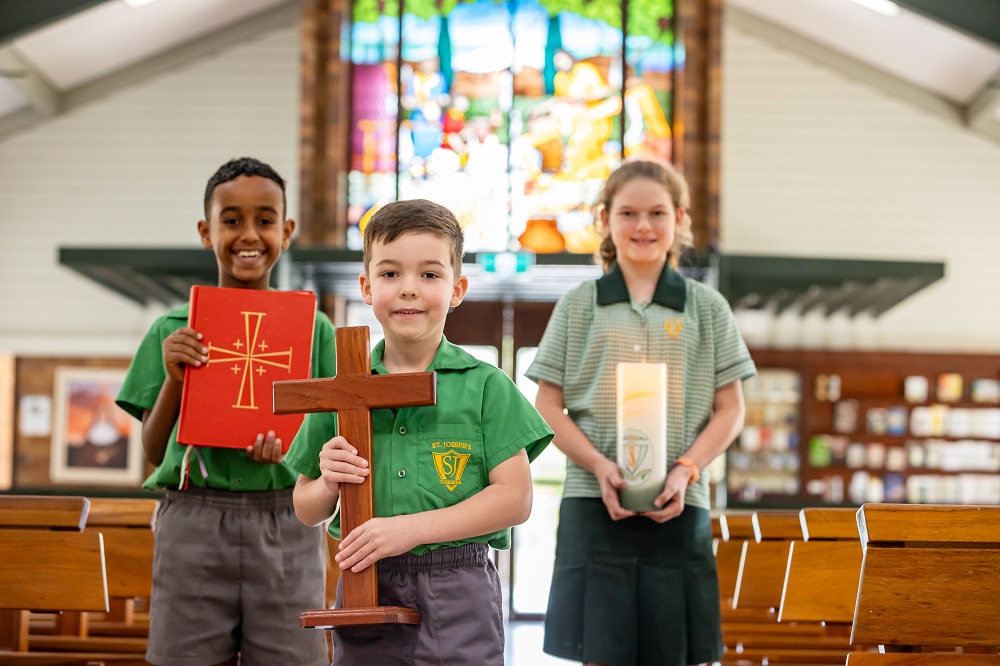 Students holding religious symbols inside a church during a school liturgy.