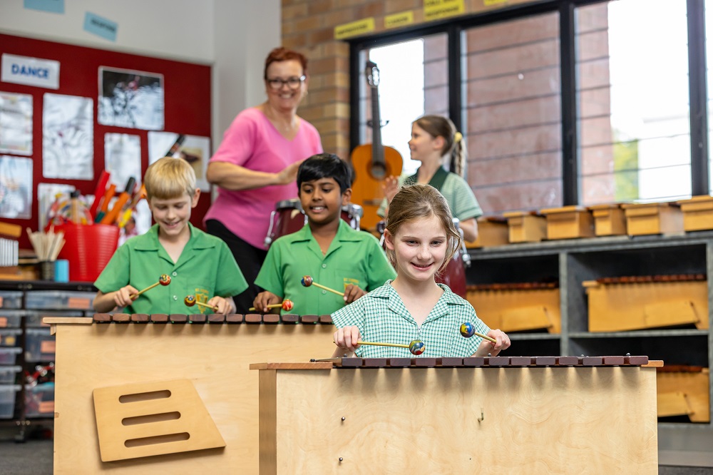 Students participating in a classroom music lesson using percussion instruments.