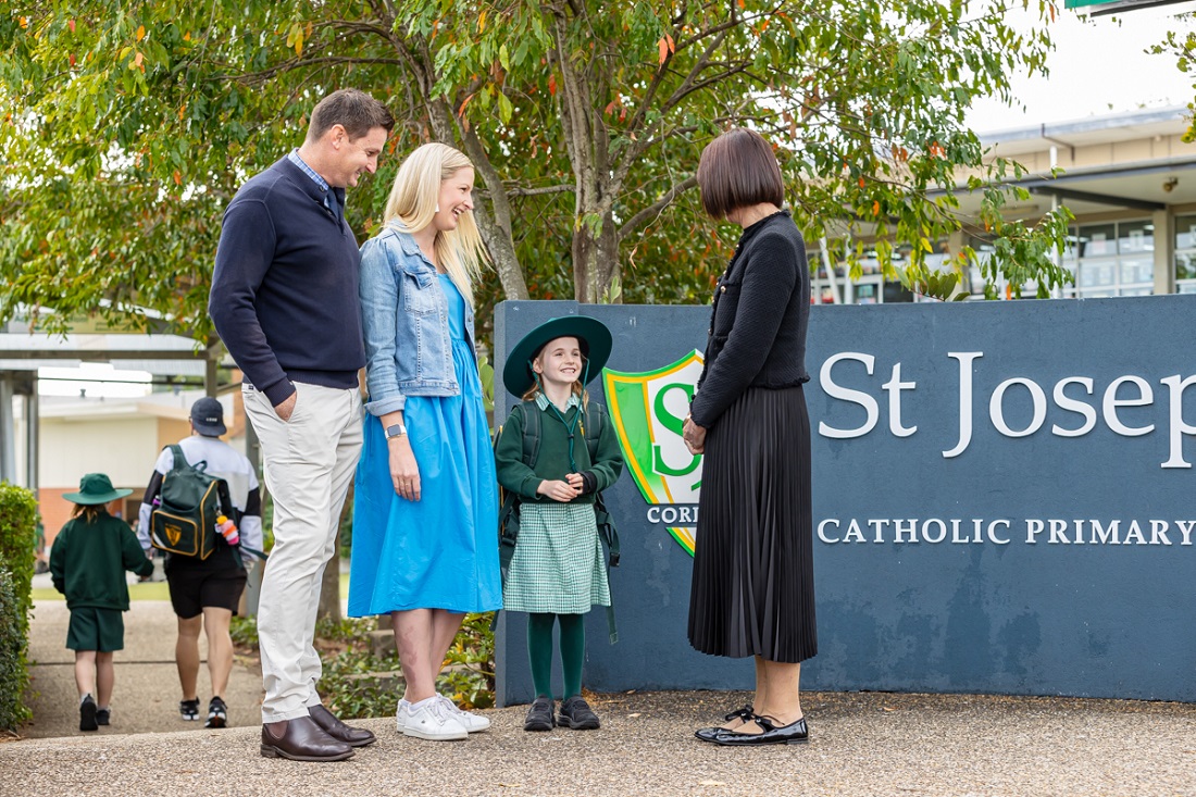 Student and adults standing near the St Joseph’s Catholic Primary School Corinda sign on school grounds.